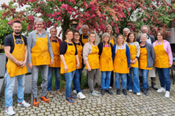 Mitarbeitende der KBS nehmen in den orangen Schürzen ihres Arbeitgebers an einem Käseseminar teil.